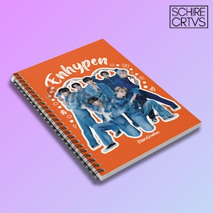 May include: Orange spiral notebook with a white graphic of a K-pop boy band, Enhypen, in a circle with white doodles around the band. The text "Enhypen" is written in white cursive on the cover.