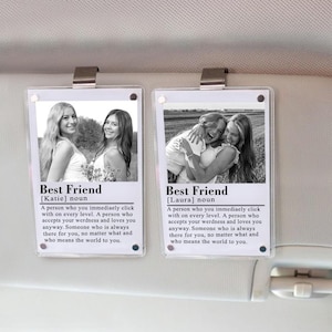 May include: Two rectangular photo plaques with metal clips. Each plaque features a black and white photo of two women, with the text "Best Friend" and a definition below. The plaques are attached to a car sun visor.