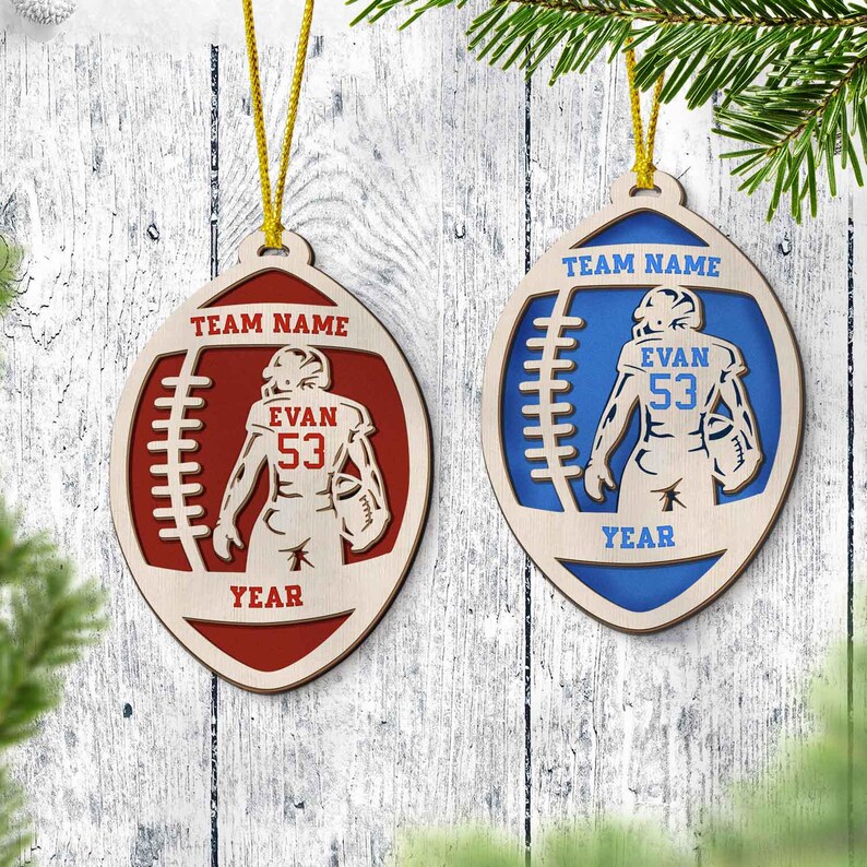 May include: Two wooden football ornaments with a player in the middle. The ornament on the left is red and says "TEAM NAME", "EVAN 53", and "YEAR". The ornament on the right is blue and says "TEAM NAME", "EVAN 53", and "YEAR".