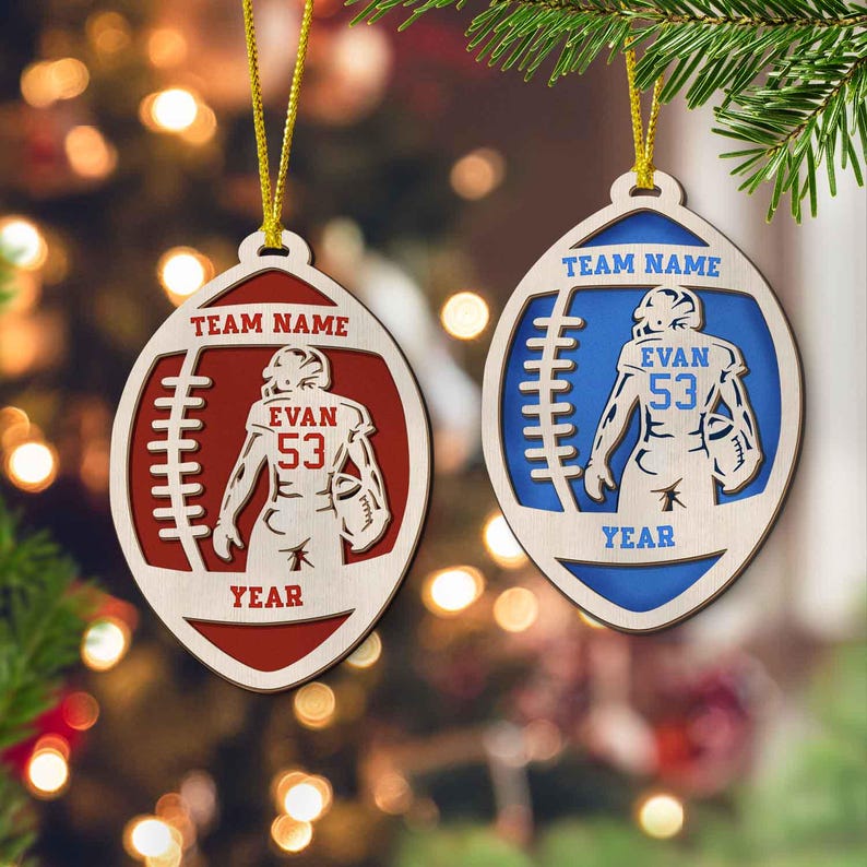 May include: Two wooden football ornaments with a player in the middle. The ornament on the left is red and says "Team Name", "Evan 53", and "Year". The ornament on the right is blue and says "Team Name", "Evan 53", and "Year".