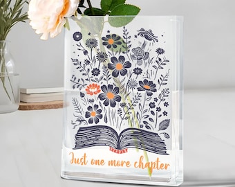 Puede incluir: Un jarrón de vidrio transparente y rectangular con un diseño floral y el texto "Just one more chapter". El diseño presenta un libro abierto con flores en azul marino, naranja y blanco. El jarrón contiene agua y flores frescas.