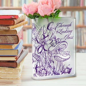 Może przedstawiać: Przezroczysty szklany wazon z fioletowym wzorem kwiatów, grzybów i kota. Wazon ma nadrukowany tekst "Through the Looking Glass".