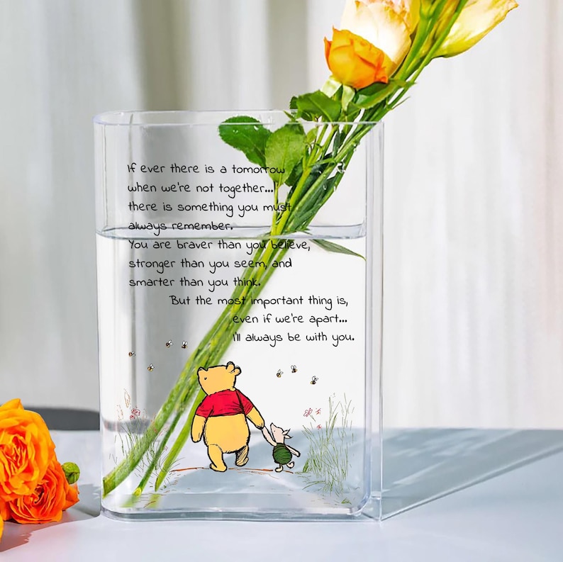 May include: A clear glass vase with a Winnie the Pooh and Piglet illustration, holding yellow and orange roses. The vase has a quote: "If ever there is a tomorrow when we're not together... I'll always be with you."