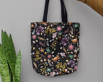 May include: A black tote bag with a colorful print of sea life, including starfish, crabs, and seaweed.