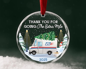 Op de afbeelding: Een ronde, doorzichtige acryl hanger aan een rood lint. Het ontwerp toont een witte postwagen met een kerstboom, een sneeuwpop en de tekst "THANK YOU FOR GOING The Extra Mile" bovenin en "2025" onderaan in een besneeuwd nachtlandschap.