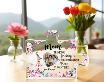 May include: A clear acrylic puzzle piece shaped like a heart with a floral design. The puzzle piece has a photo of three women in the center. The text "Mom" is at the top of the puzzle piece, and the text "Thank you for being such an important piece of my life" is below the photo. The text "Love, Emma" is at the bottom of the puzzle piece.