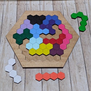 May include: A wooden hexagonal puzzle with a variety of colored hexagonal pieces. The puzzle is made up of 27 pieces, each with a different color. The pieces are arranged in a spiral pattern, with the colors alternating. The puzzle is a fun and challenging way to exercise your brain.