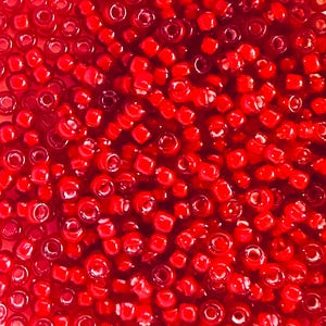 May include: A large quantity of small, red, round glass beads. The beads are opaque and have a slight shine.