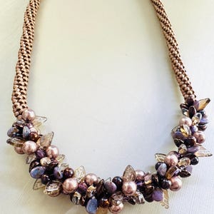 May include: A brown beaded necklace with a cluster of purple, brown, and clear beads.