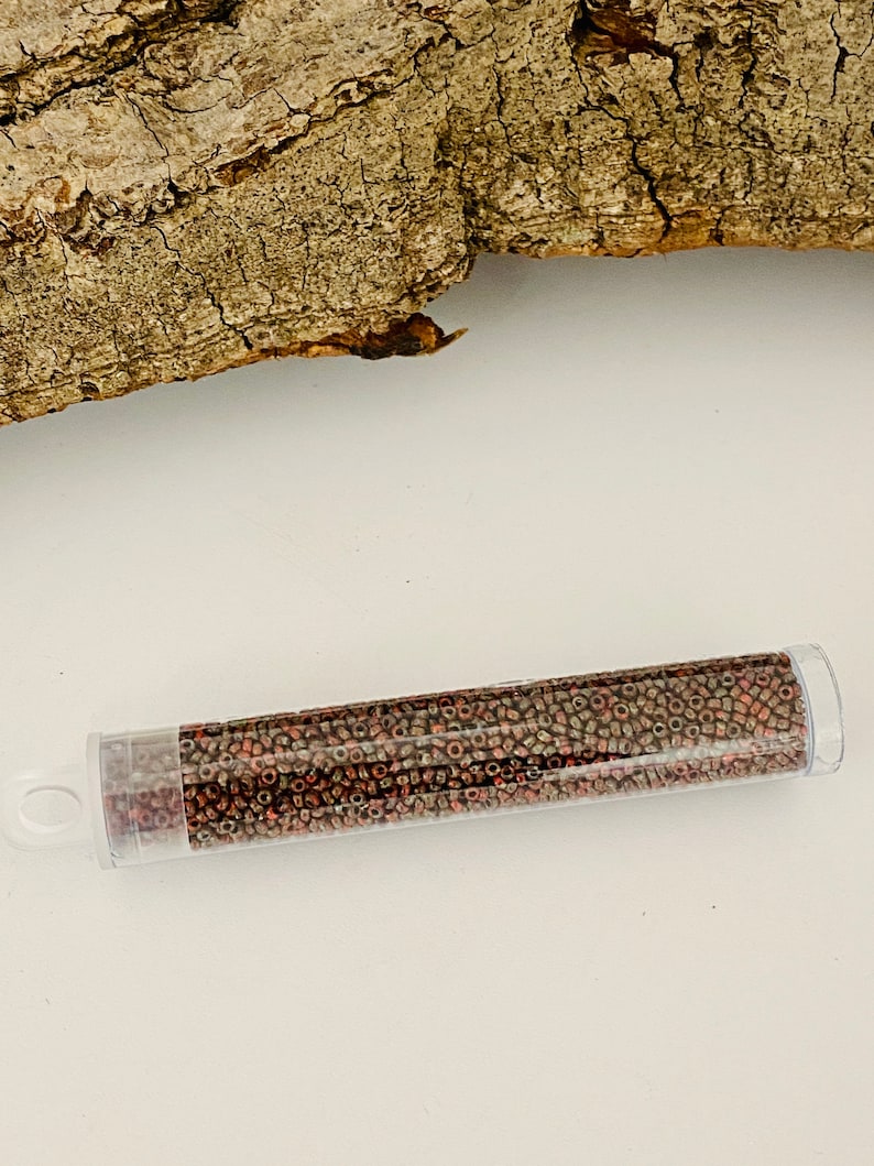 May include: A clear plastic tube filled with small, round, copper-coloured beads. The beads have a metallic sheen and are arranged in a random pattern.