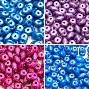 May include: Assortment of four colors of seed beads. The beads are small and oval shaped with a hole in the center. The colors are blue, purple, pink, and turquoise.