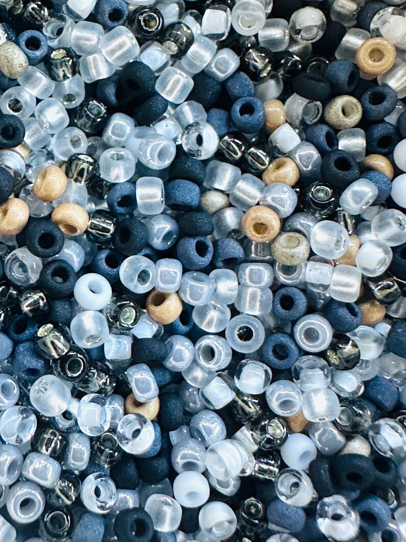 May include: A close-up image of a variety of small, round beads in shades of blue, white, and brown. The beads are arranged in a random pattern, creating a textured and colorful background.