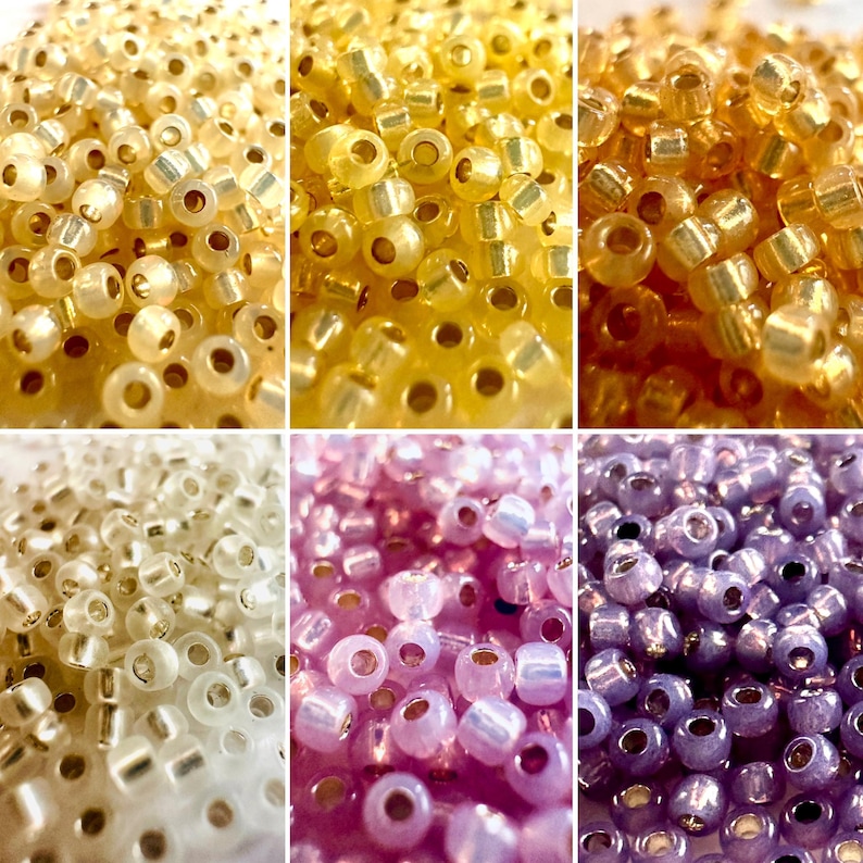 May include: Close-up of six sections of seed beads in various colors. The colors include gold, yellow, white, pink, and purple. The beads are small, round, and have a hole through the center for stringing.