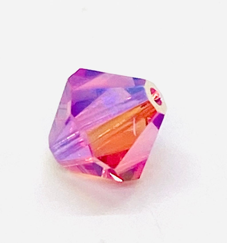 Peut inclure: Une seule perle de cristal iris&eacute;e violette et orange avec un design facett&eacute;.