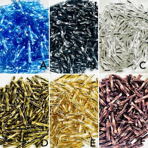 May include: Six piles of glass tube beads in various colours: blue, black, silver, gold, light gold, and copper. The beads have a twisted, textured design. The image shows a selection of beads for crafting or jewellery making.
