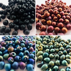 May include: Assortment of small, oval-shaped glass beads in four colours: black, copper, teal, and iridescent blue. The beads have a matte finish and are perfect for jewellery making.