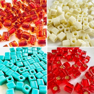 May include: Assortment of colorful square beads in red, white, blue, turquoise, and cream. The beads are made of glass and have a smooth, polished finish.