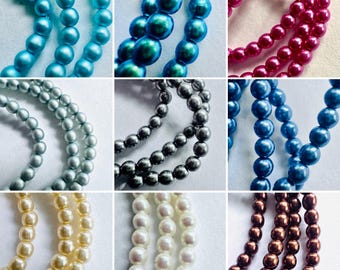 May include: A collection of nine distinct strands of round, smooth beads in various colors including light blue, iridescent teal, magenta, silver, dark gray, royal blue, cream, white, and bronze, arranged in a grid of individual squares.