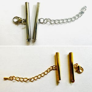 May include: Two sets of jewelry tube clasps, one silver-toned and one gold-toned. Each set includes a cylindrical tube connector, a lobster claw clasp, and an adjustable extender chain with circular links for securing necklaces or bracelets.