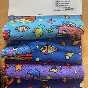 May include: A stack of four fabric swatches featuring a colorful sea life print. The fabric is 100% cotton and is 44/48 inches wide. The colors include turquoise, royal blue, lilac, and navy. The print features fish, starfish, seashells, and bubbles.