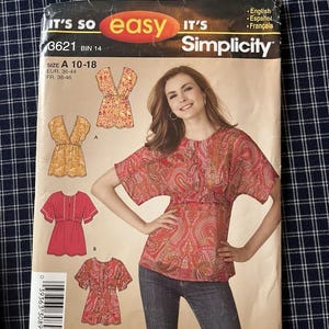 May include: Simplicity sewing pattern for a top, size A 10-18. The pattern features a woman wearing a red paisley top. The pattern includes illustrations of different top styles. The text "IT'S SO easy" is visible.