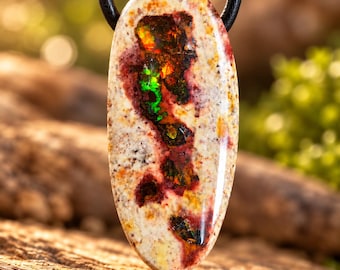 May include: An oval-shaped pendant featuring a cream-colored stone with speckled brown and red inclusions. The center displays a vibrant, iridescent patch with flashes of bright green, orange, and red. The pendant hangs from a black cord.