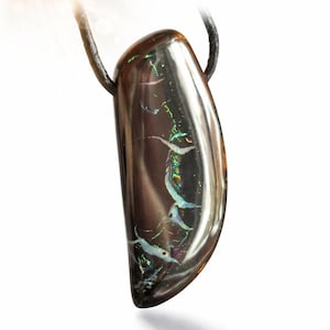 May include: A polished, teardrop-shaped pendant with a dark, iridescent surface. The pendant is suspended from a black cord. The surface displays flashes of green, blue, and white, creating a striking visual effect. The pendant is set against a white background.