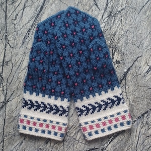 May include: A pair of knitted mittens in shades of blue, white, and pink. The mittens feature a repeating pattern of small pink hearts on a blue background. The cuffs have a white band with a geometric design and a pink and blue border.