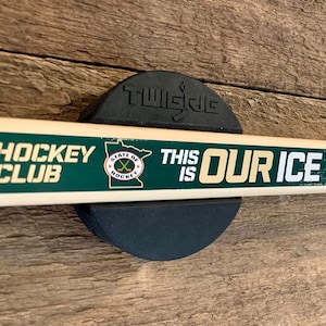 An autographed MN Wild hockey stick mounted to a wall with the TwigRig hockey stick holder