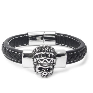 Könnte beinhalten: Schwarzes Lederarmband mit einem silbernen Totenkopf-Anhänger. Der Totenkopf trägt ein Kopfschmuck mit Federn. Das Armband hat einen Magnetverschluss.