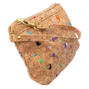 May include: A small cork handbag with a colorful confetti pattern and a gold zipper. The bag has a short strap and a gold clasp.