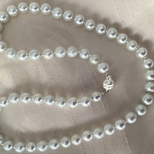 Puede incluir: Un collar de perlas blancas con un cierre plateado.