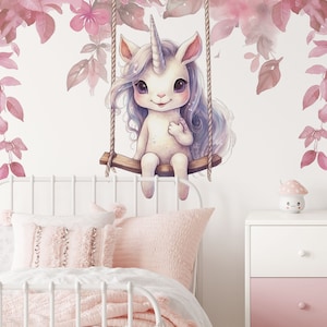 May include: A white unicorn with a pink horn and blue hair sits on a swing made of rope and wood. The unicorn is surrounded by pink flowers and leaves.