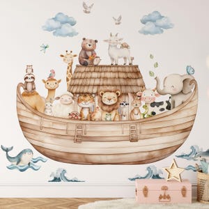 Peut inclure: Un grand autocollant mural représentant une arche en bois remplie d'animaux à l'aquarelle, dont un lion, un tigre, un éléphant, une girafe et un ours. La scène inclut des nuages bleus, des oiseaux en vol et des vagues stylisées avec une baleine.