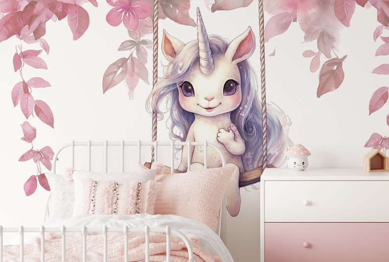 May include: A white unicorn with a pink horn and blue mane sits on a swing in front of a pink floral wall. The unicorn has large, dark eyes and a sweet expression. The swing is made of rope and wood.