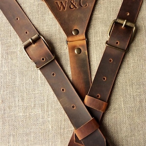 May include: Brown leather camera strap with metal buckles and the initials "W&C" embossed on the front.