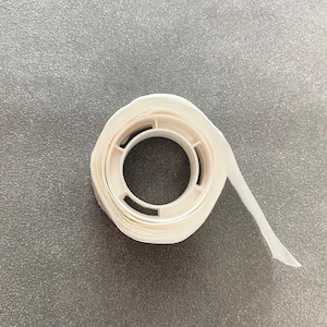 May include: A roll of white double-sided tape with a dispenser.