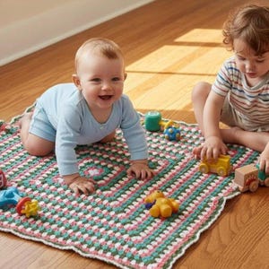 May include: A square crochet blanket featuring a repeating granny square pattern in shades of pink, green, and white with a scalloped white border. The blanket is scattered with various small plastic and wooden toy vehicles and figures.