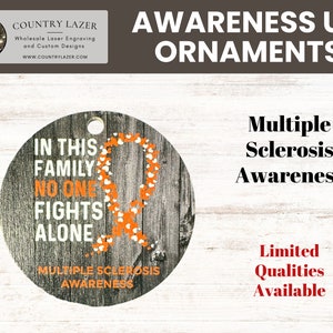 May include: A round wooden ornament with a white background and orange text that reads "In this family no one fights alone". The ornament also features an orange ribbon with white hearts, representing Multiple Sclerosis Awareness.