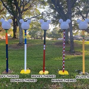 Tall outdoor lamps. The top is what and looks like a Mickey Mouse silhouette. The poles for the lamps are themed to popular characters.