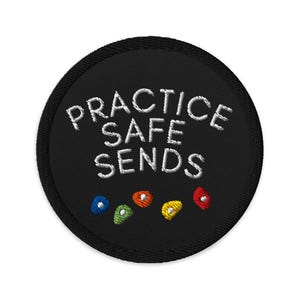May include: Black round embroidered patch with white text that reads "PRACTICE SAFE SENDS" and five colorful climbing holds.