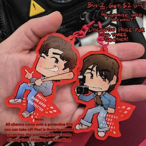 May include: Two red acrylic charms featuring cartoon illustrations of characters. One holds a baseball bat, the other a camera. Text on the charms reads "Pretty Damn Good Babysitter" and "Capture the Right Moment."