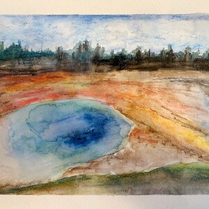 Könnte beinhalten: Aquarellmalerei eines blauen Sees mit einem grünen Grasufer und einer fernen Skyline einer Stadt im Hintergrund. Der See ist von einer farbenfrohen Landschaft aus Rot, Orange und Gelb umgeben.
