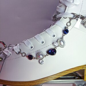 May include: White roller skate with a silver chain and blue and white crystal embellishments.