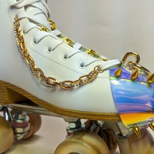 May include: White roller skate with gold chain detail and an iridescent, spiked toe stop.