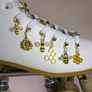 May include: White roller skate with gold and black bee, honeycomb, and sunflower charms attached to the laces.