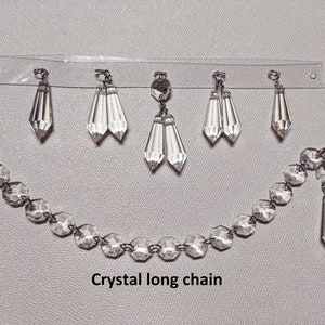 May include: A crystal long chain with multiple crystal drops hanging from a clear plastic strip. The chain is made of faceted crystal beads and has a single crystal drop hanging from the end. The text "Crystal long chain" is printed below the chain.