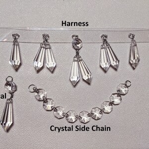 May include: A set of crystal embellishments for a garment. The set includes a harness with multiple crystal drops, a crystal side chain, and a single crystal drop.