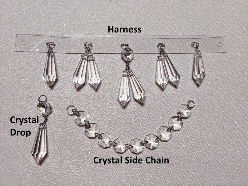 May include: A set of crystal embellishments for a garment. The set includes a harness with multiple crystal drops, a crystal side chain, and a single crystal drop.