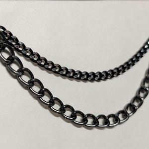 Peut inclure: Un accessoire de cha&icirc;ne &agrave; deux brins, de couleur m&eacute;tal de canon. La cha&icirc;ne sup&eacute;rieure est une cha&icirc;ne plus petite et plus d&eacute;licate, tandis que la cha&icirc;ne inf&eacute;rieure pr&eacute;sente des maillons plus grands et de forme ovale. Un anneau de couleur argent&eacute;e relie les cha&icirc;nes en haut.